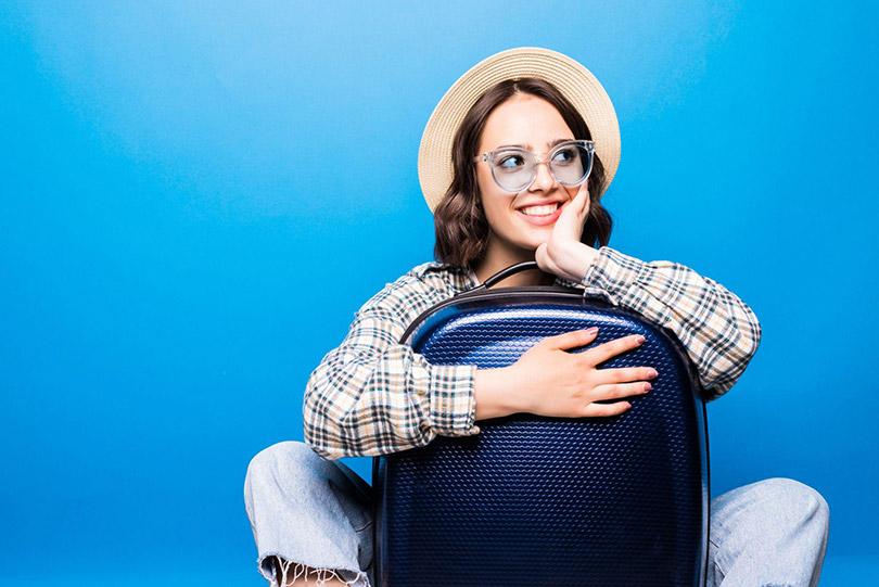 Mulher com mala e chapéu pronta para viajar