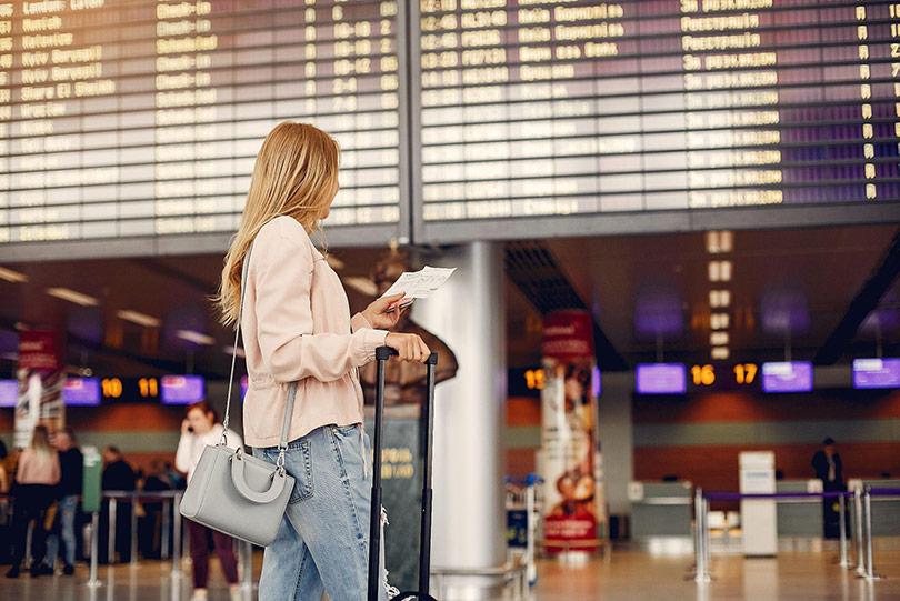 Mulher no aeroporto olhando bilhete de passagem