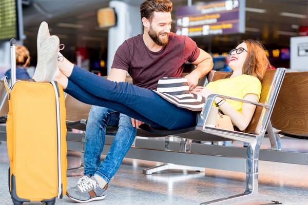 Casal esperando em aeroporto com bagagem de mão