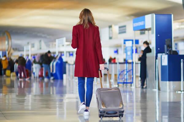 Mulher caminhando em aeroporto com bagagem de mão