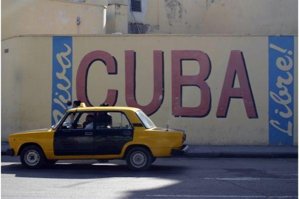 carro amarelo na frente de pintura em muro escrito cubra libre