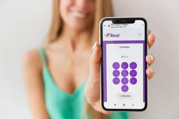 Mulher segurando smartphone com o aplicativo da Real Seguro Viagem