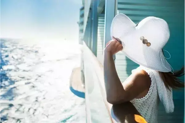 Mulher usando chapéu branco olhando o mar