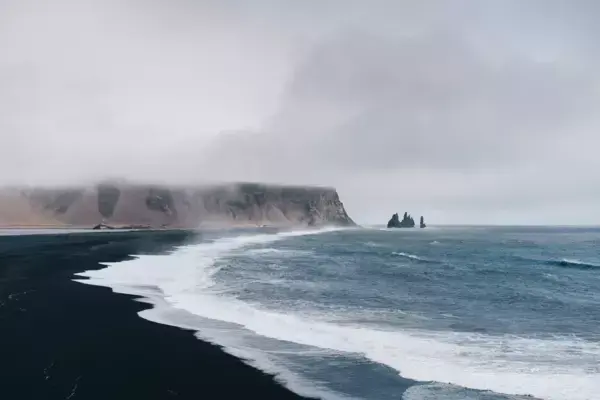 Mar e areia preta em praia da Islândia