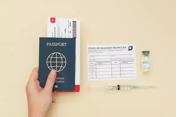 Mãos segurando passaporte, passagens, e comprovante de vacinação da Covid-19