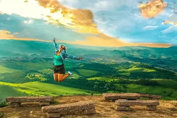 Fefa pulando com paisagem de Socorro, em São Paulo, ao fundo