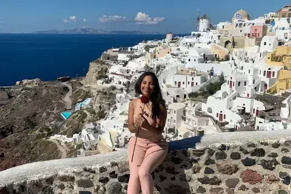 Bruna na Grécia, com casas típicas do país ao fundo