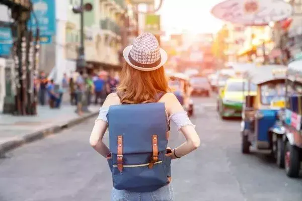 Mulher usando chapéu, de costas, em rua movimentada