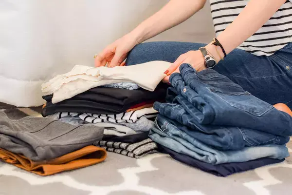 Mulher dobrando roupas para colocar na mala