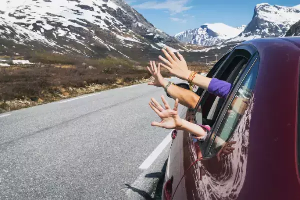 família com mãos para fora da janela em viagem de carro