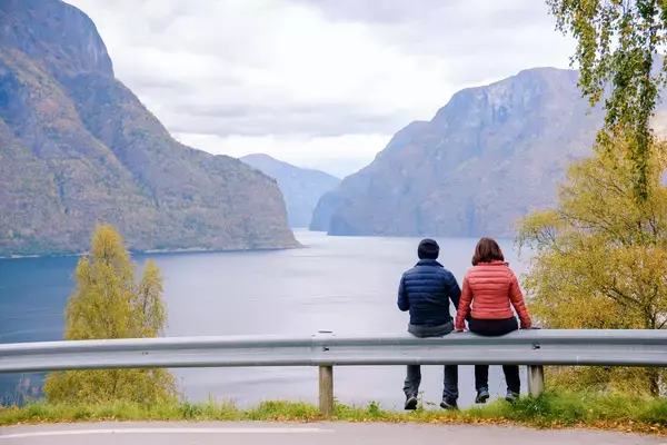 Casal apreciando a vista de um rio entre montanhas na beira de uma estrada