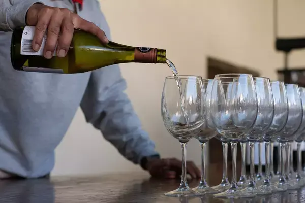 Homem servindo taças enfileiradas com vinho