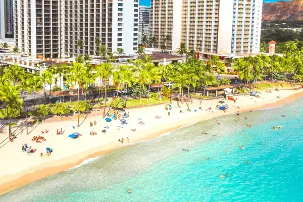 Foto de uma das praias de Cancún, no México, com vista pra vários prédios e coqueiros.