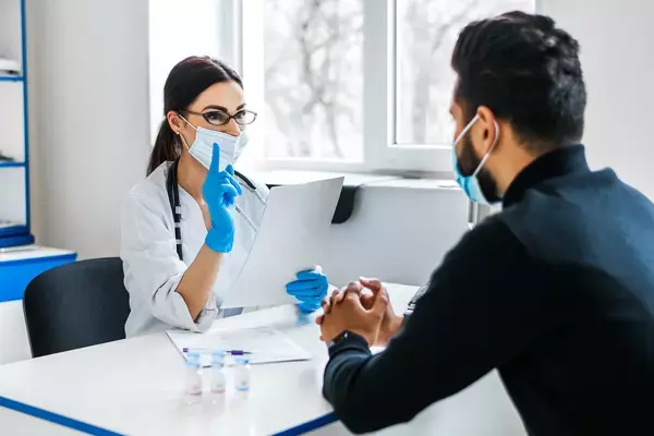Médica atendendo homem em consultório
