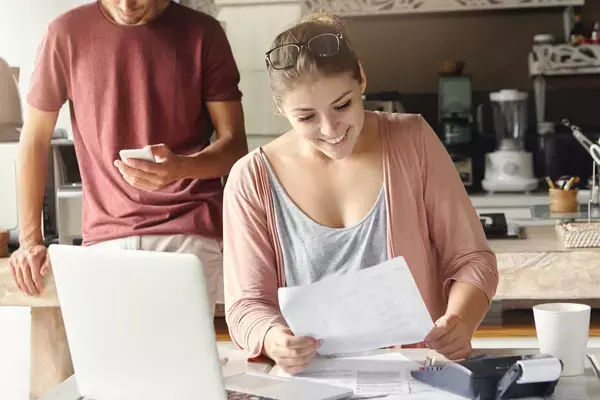 Mulher lendo documento enquanto marido olha o celular