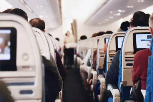 Foto de vários passageiros sentados dentro de um avião durante o voo.