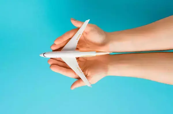 Um par de mãos segurando um avião em miniatura.