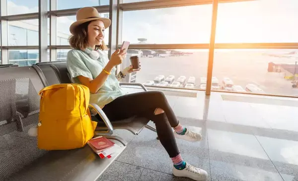 Uma moça esperando na sala de embarque de um aeroporto.