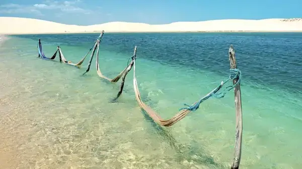 Várias redes apoiadas em troncos no mar azul.