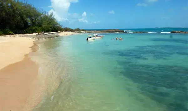 Uma praia com areias brancas e mar azul claro.