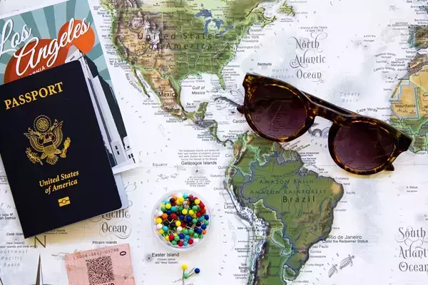 Imagem de um mapa com alguns objetos típicos de viagem em cima, como passaporte e óculos de sol.