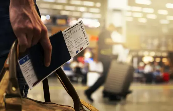 Uma foto focada na mão de um viajante segurando um passaporte.