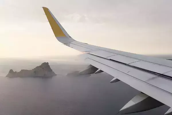 Foto de uma das asas de um avião, vista através da janela enquanto ele decola.