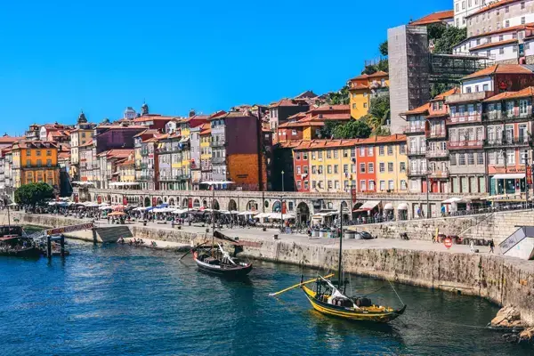 Foto de casas próximas ao mar, com alguns barquinhos a remo na água, em Porto, Portugal.