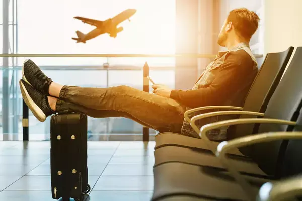 Homem sentado em aeroporto vendo decolagem de avião