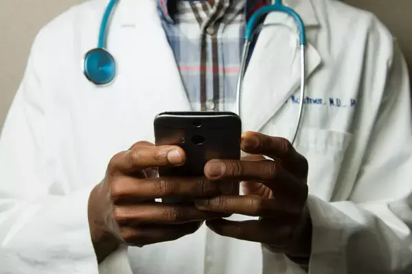 Médico com celular na mão realizando teleatendimento