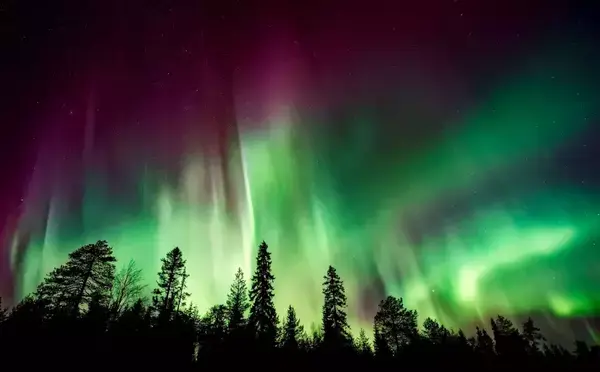 Imagem de uma aurora boreal verde e roxa.
