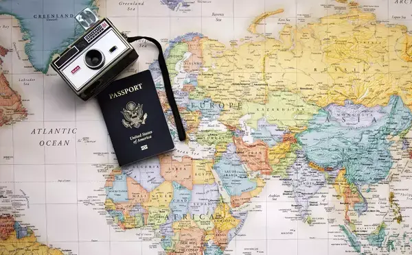Uma câmera e um passaporte em cima do mapa mundi.