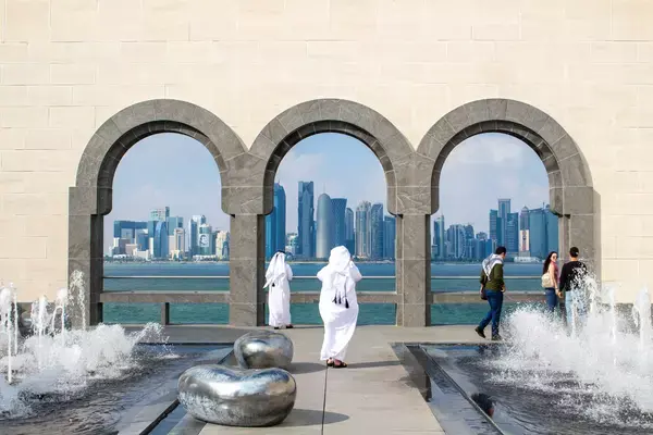 Homens com roupas árabes em construção em frente aos prédios da cidade de Doha, no Catar