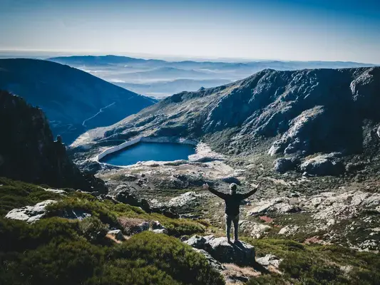 Homem de braços abertos em frente a lago na Serra da Estrela, Portugal