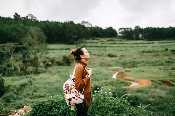 Mulher com mochila nas costas em área externa com aspecto de tranquilidade