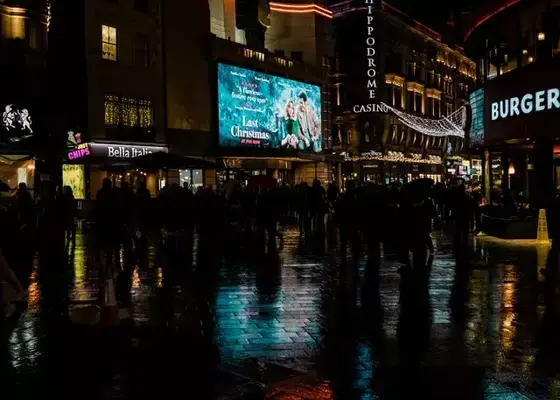 Movimentação na Leicester Square durante a noite, com luzes dos cinemas e cassinos