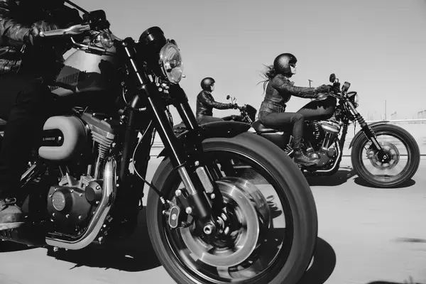 Foto em preto e branco de motociclista com roda de moto em primeiro plano