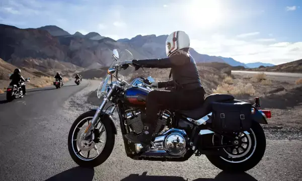 Pessoa dirigindo moto em estrada com outros motociclistas mais a diante