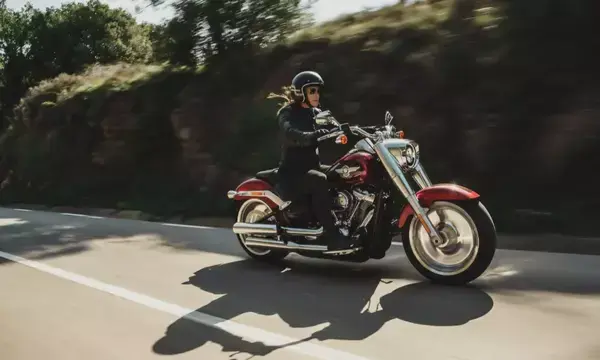Mulher em uma moto vermelha em estrada