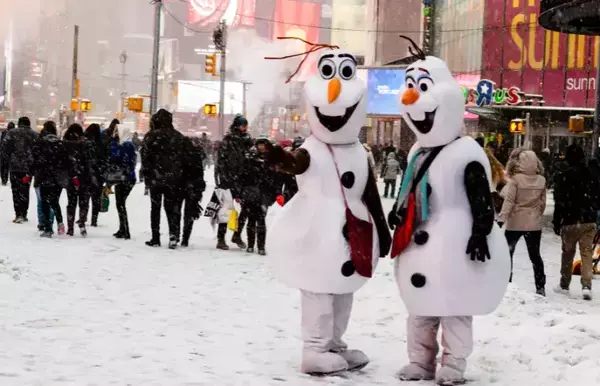 Bonecos de neve conversando perto de turistas.