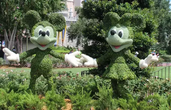 Mickey e Minnie em escultura na grama.
