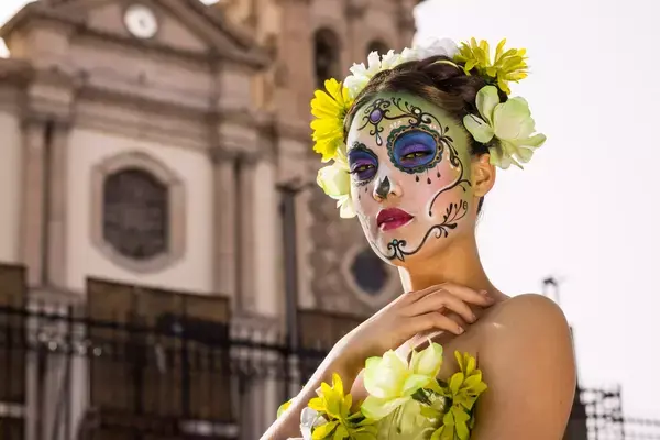 Mulher com maquiagem típica do dia de los muertos em frente a igreja no México