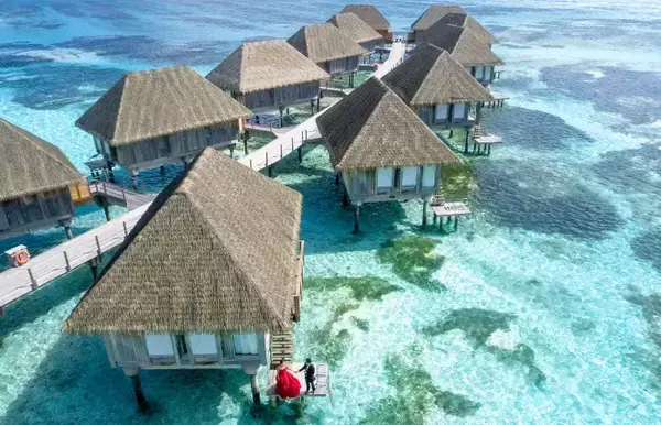 Várias cabanas sob as águas azuis do mar de Maldivas.