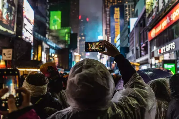 Pessoa com celular na mão tirando foto da virada de ano na Times Square, Nova York
