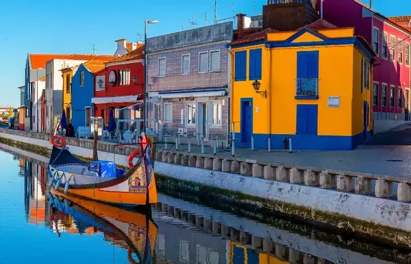 barcos às margens de um rio, e casas coloridas perto deles.
