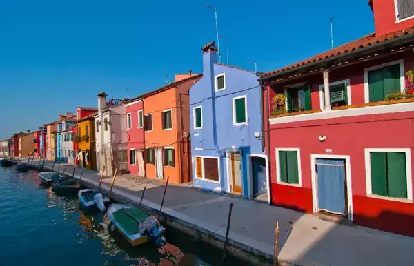 barcos às margens de um rio, e casas coloridas perto deles.