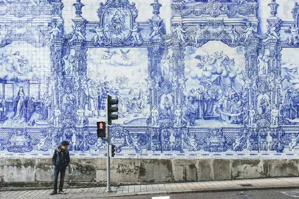 Homem em pé em frente a mural com azulejos portugueses em Porto, Portugal