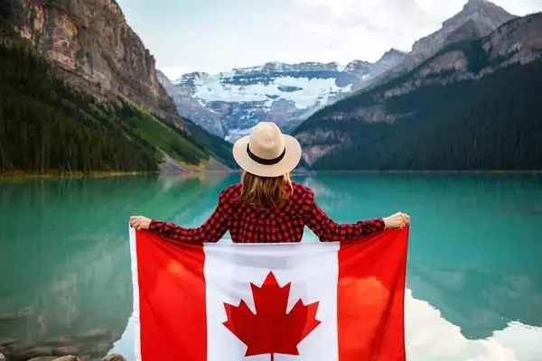 mulher em um barco, no lago, segurando a bandeira do canadá