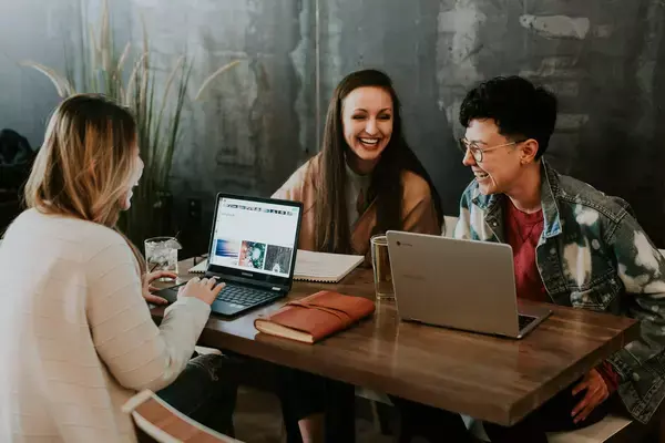 Estudantes intercambistas rindo ao redor de uma mesa com livros e notebooks