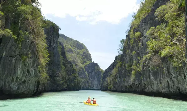 Pessoas em caiaque entre grandes rochas nas águas transparentes de El Nido, nas Filipinas